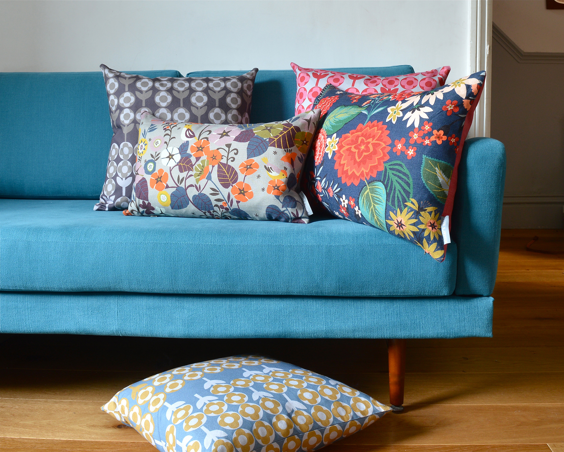 Blue couch with four patterned pillows and one on the floor