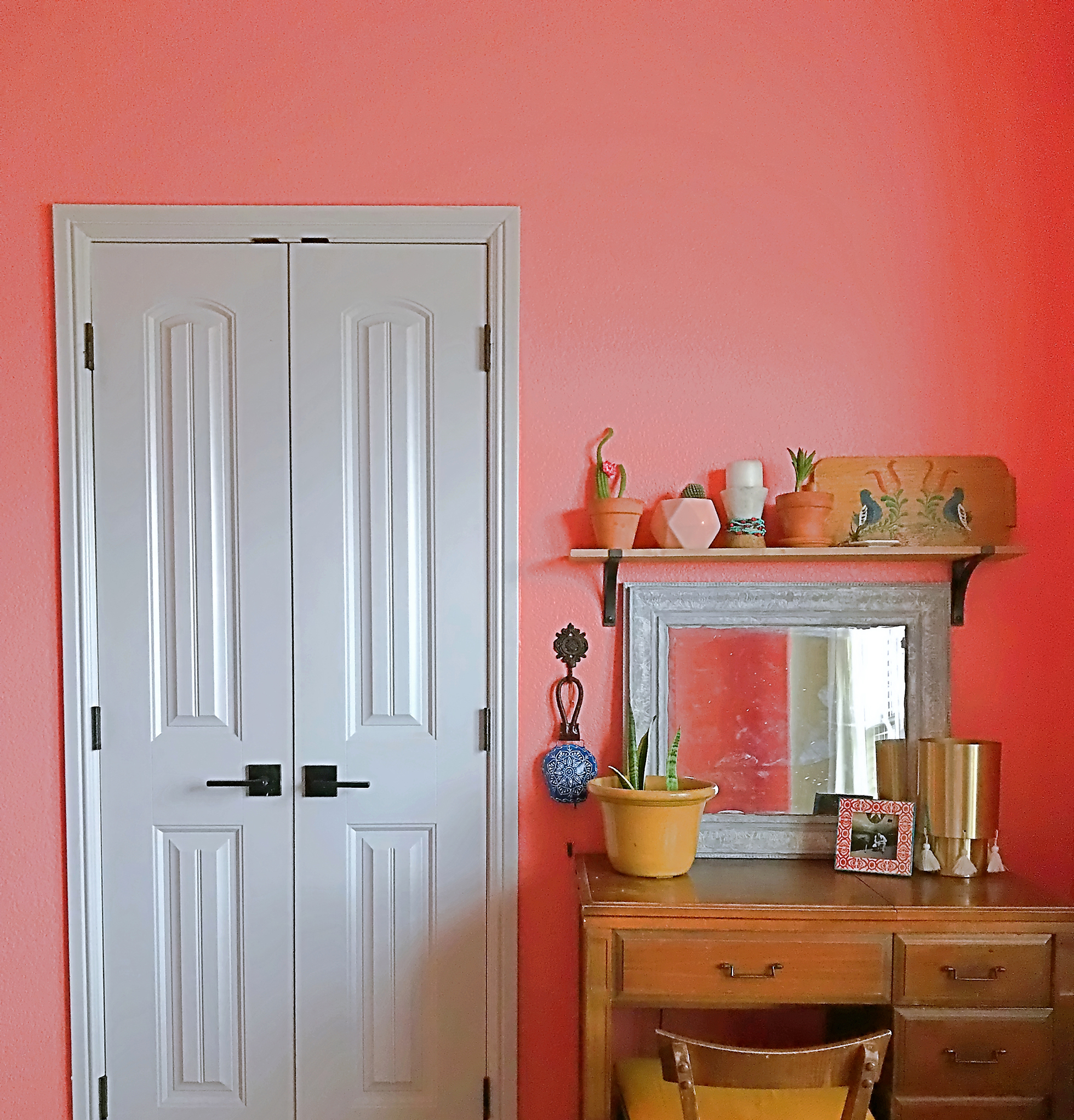Brown wood desk in front of salmon wall with white door