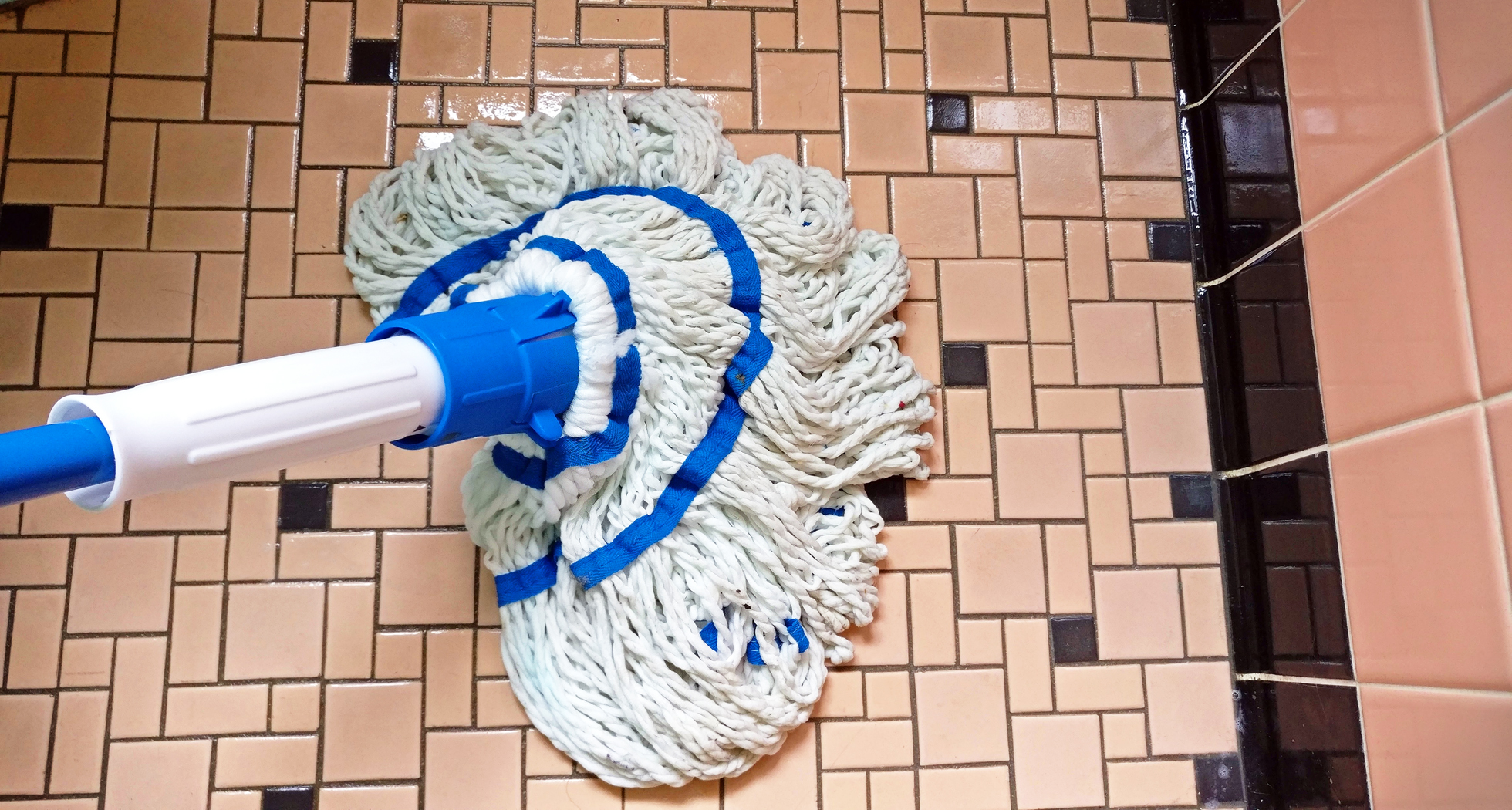 String mop on a vintage bathroom tile floor