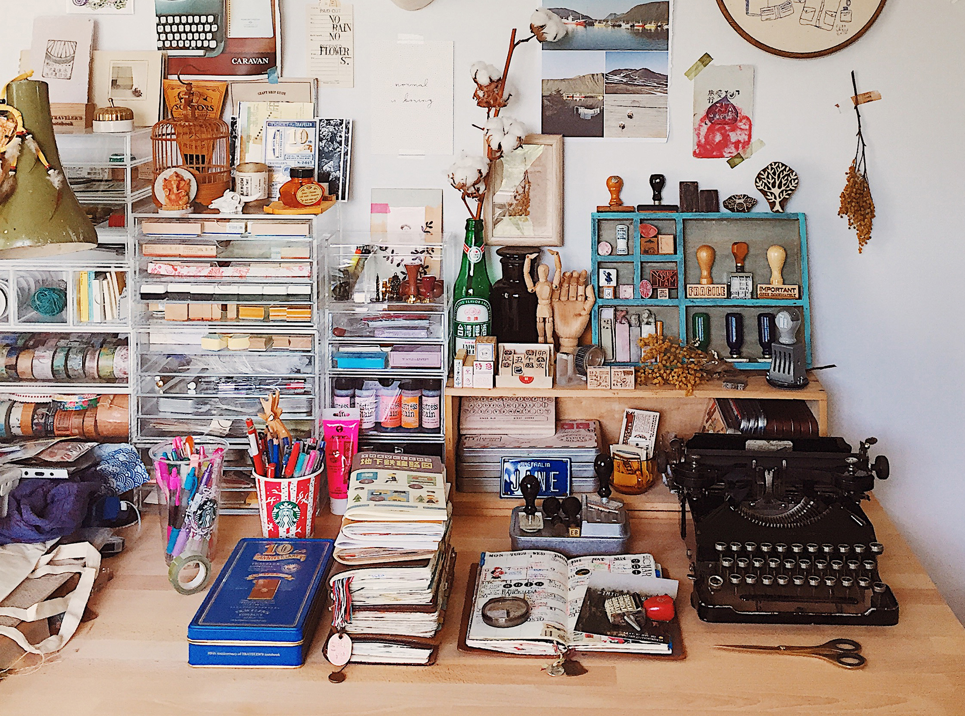 Desk crowded with stamps, notebooks, typewriter, and objects