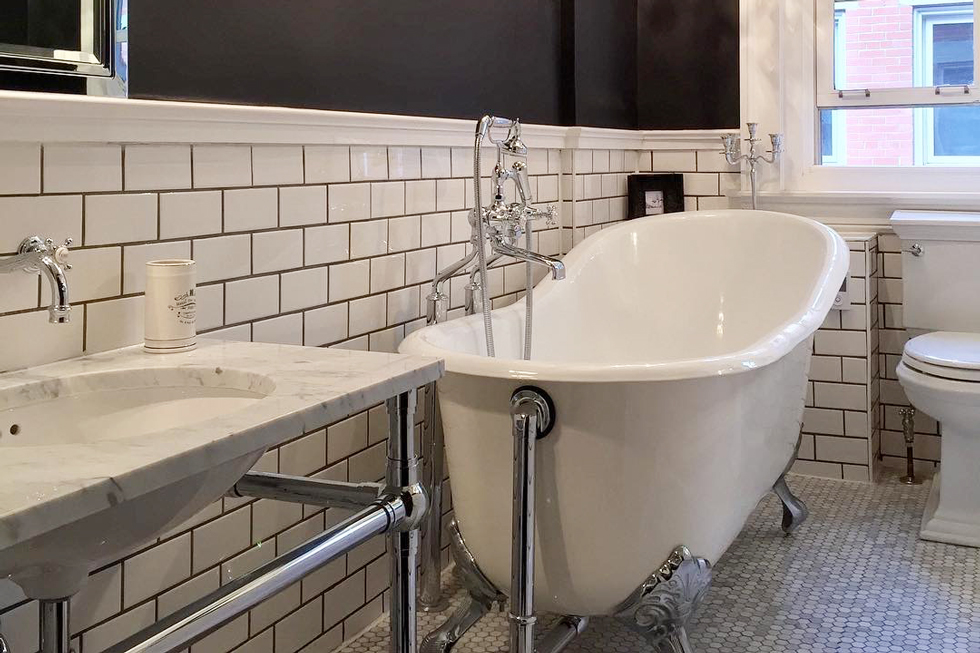 A white clawfoot tub in a restored tiled bathroom