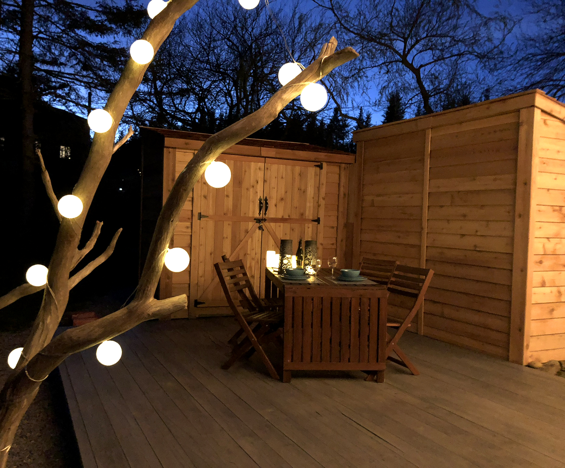 Wood deck with table illuminated by tree with globe lights