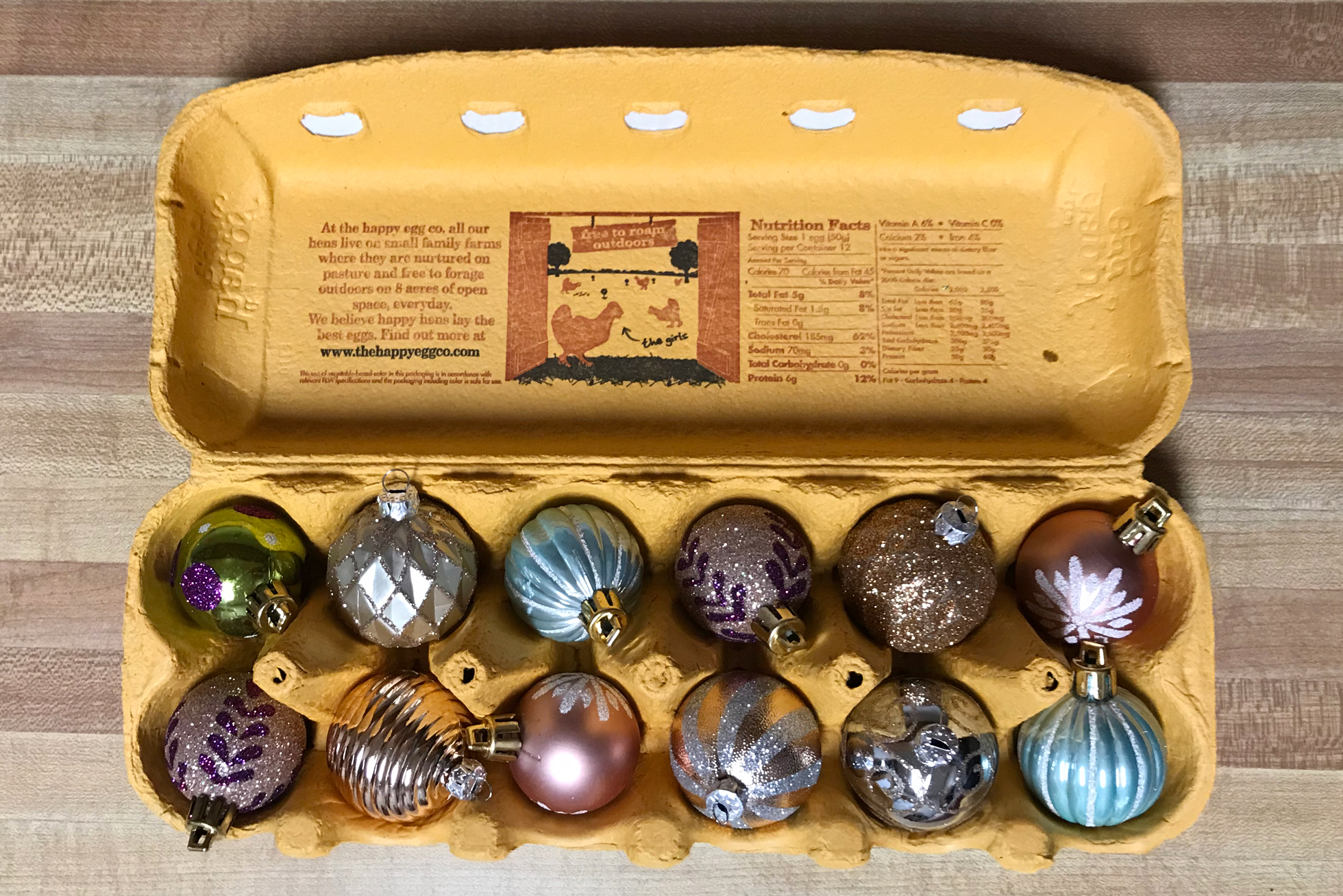 Small colorful ornaments in a yellow egg carton
