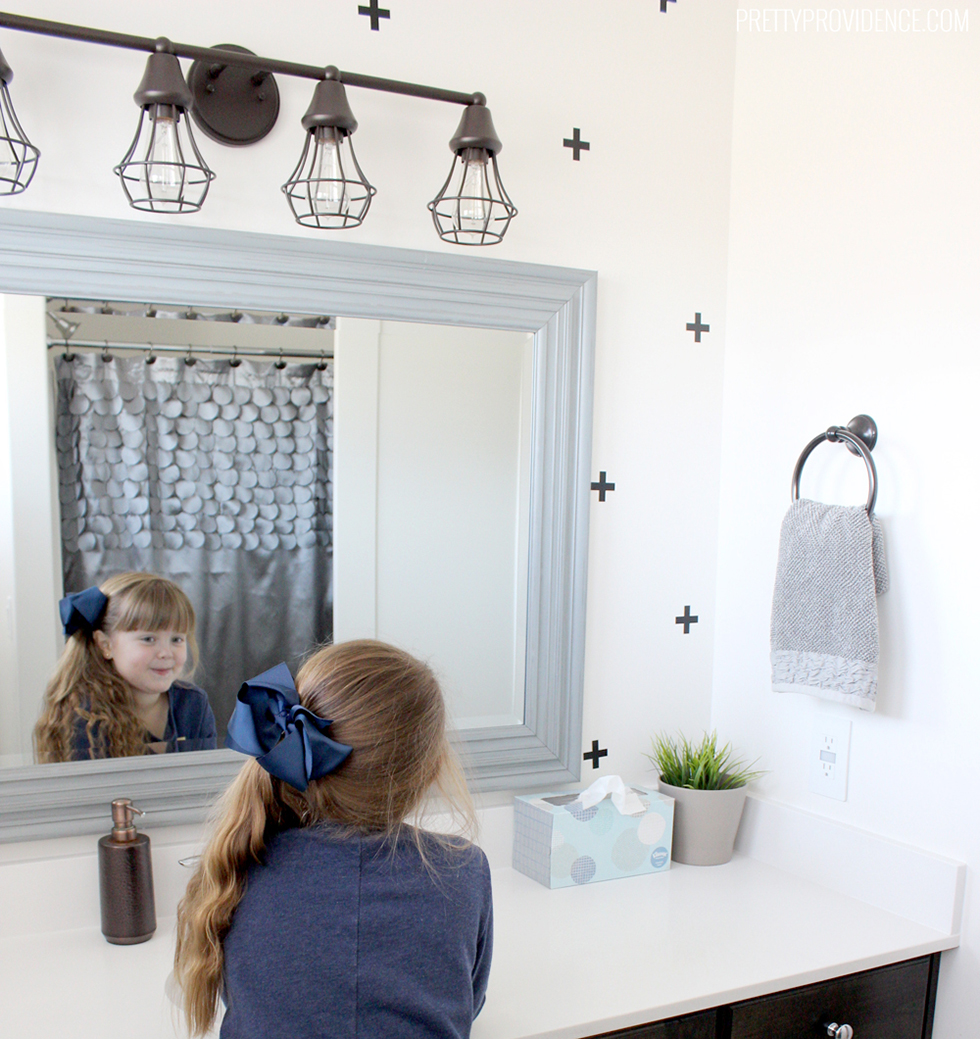 Child looking in mirror of white bathroom with black crosses