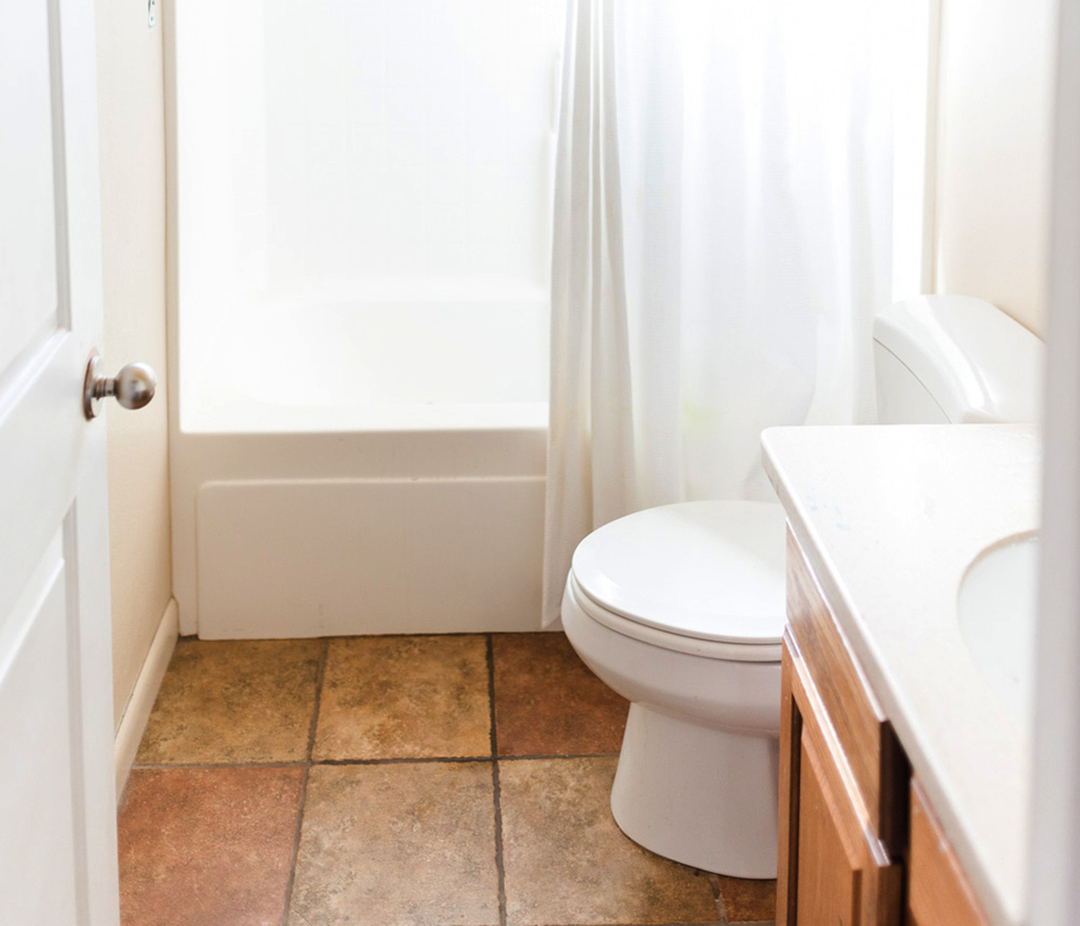 An all-white bathroom with orange faux stone tiles