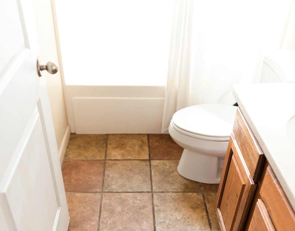 An all-white bathroom with orange faux stone tiles