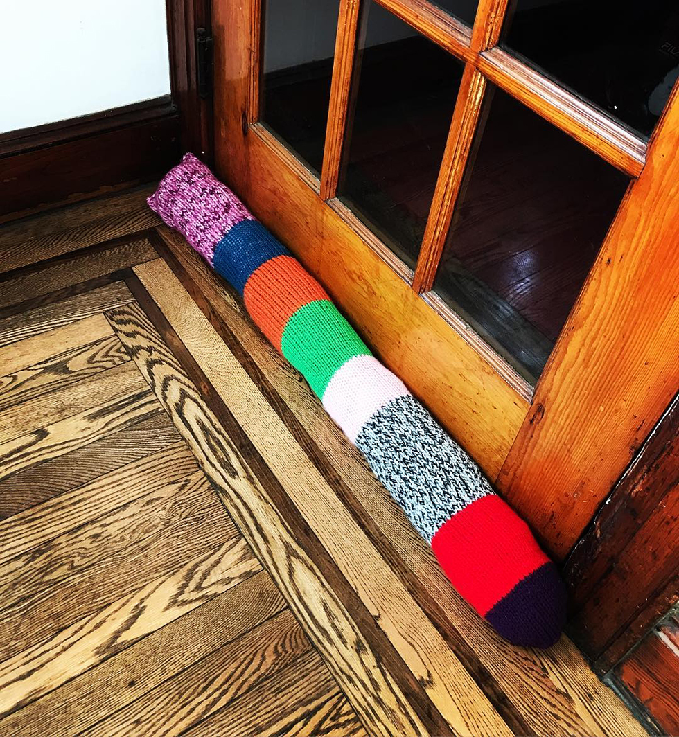 Multi-colored knit door snake on wood floor | DIY Insulation
