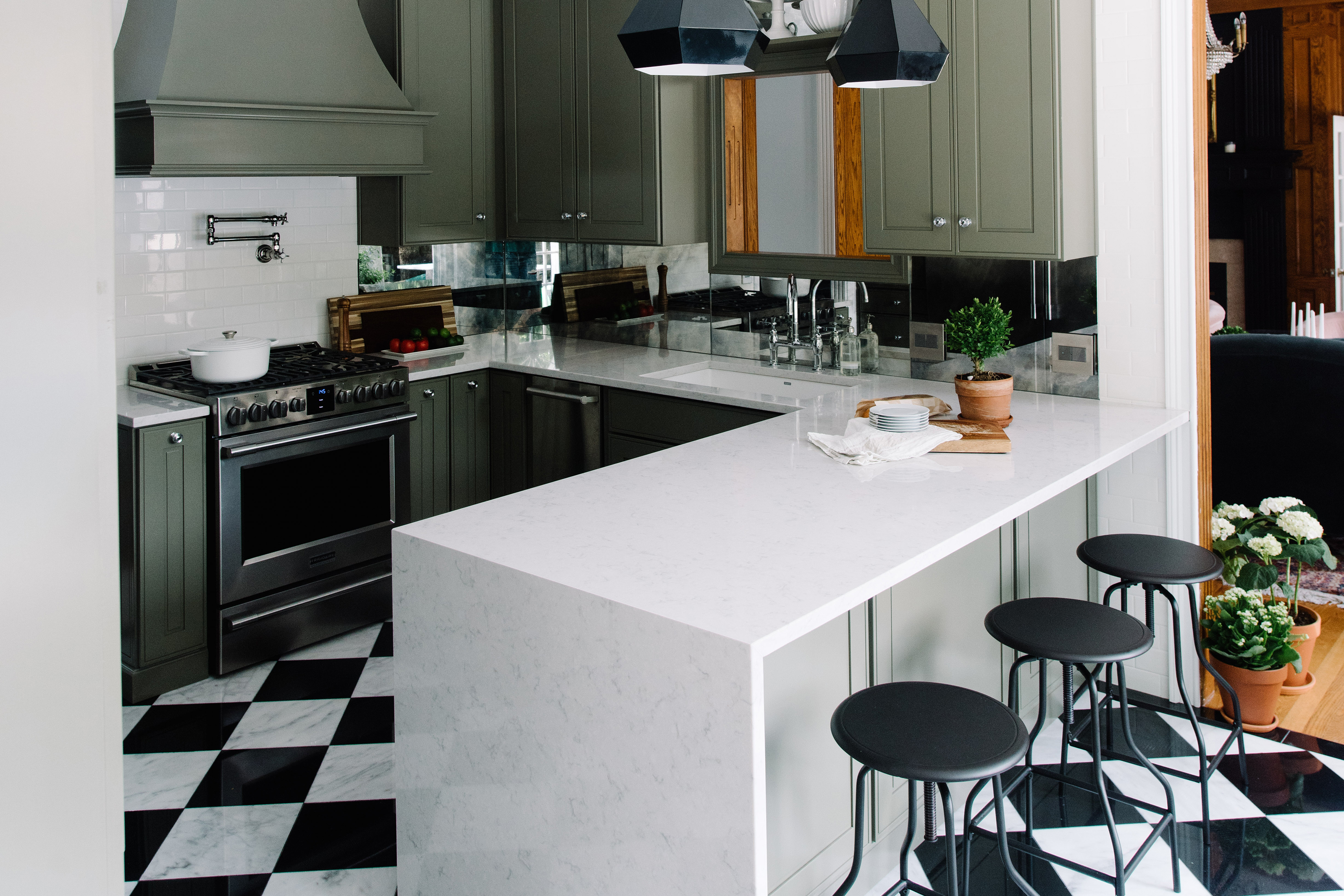 Updated kitchen with green cabinets, black and white floor