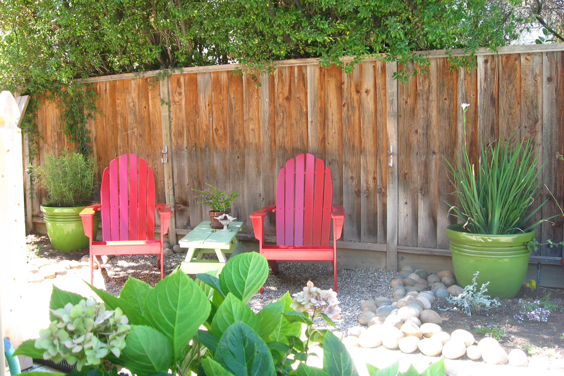 Red Adirondack chairs in a gravel backyard