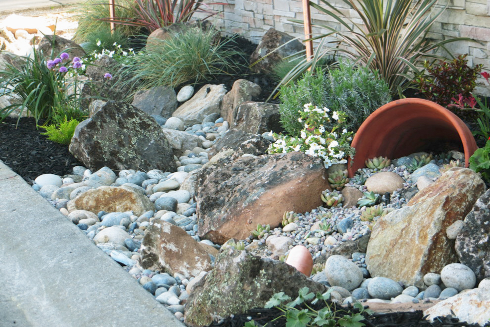 Low water landscape with gray rocks next to a sidewalk