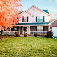 A beautiful house with a tree changing colors for Fall in front of it.