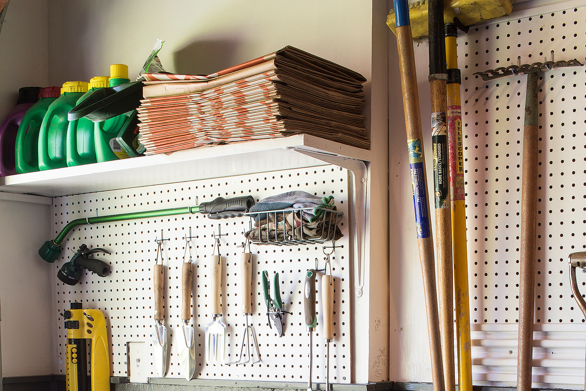 A white pegboard with hanging tools in a garage