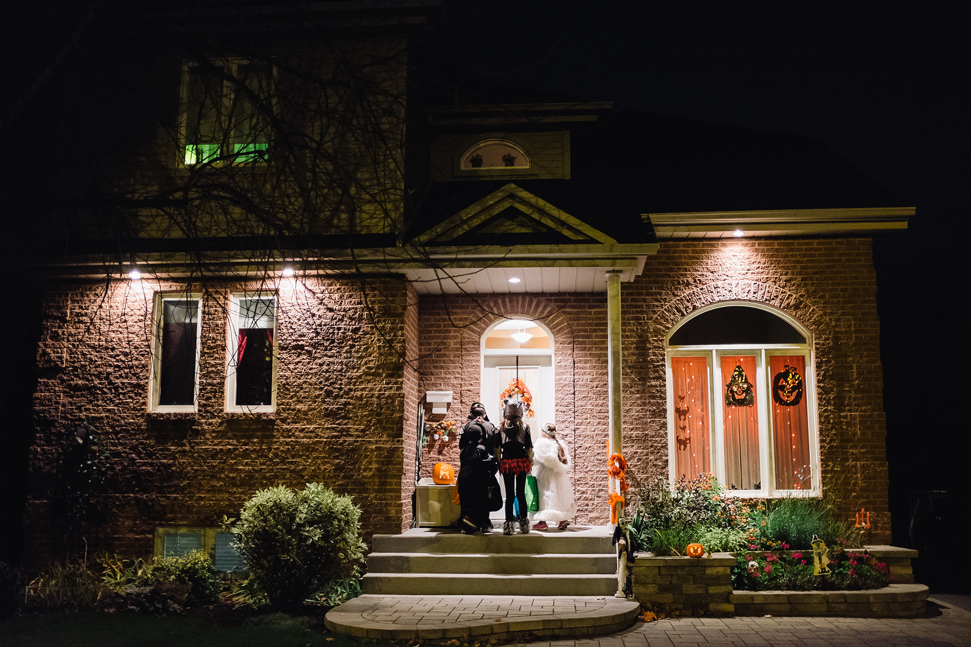 Three trick-or-treaters waiting on a doorstep on Halloween