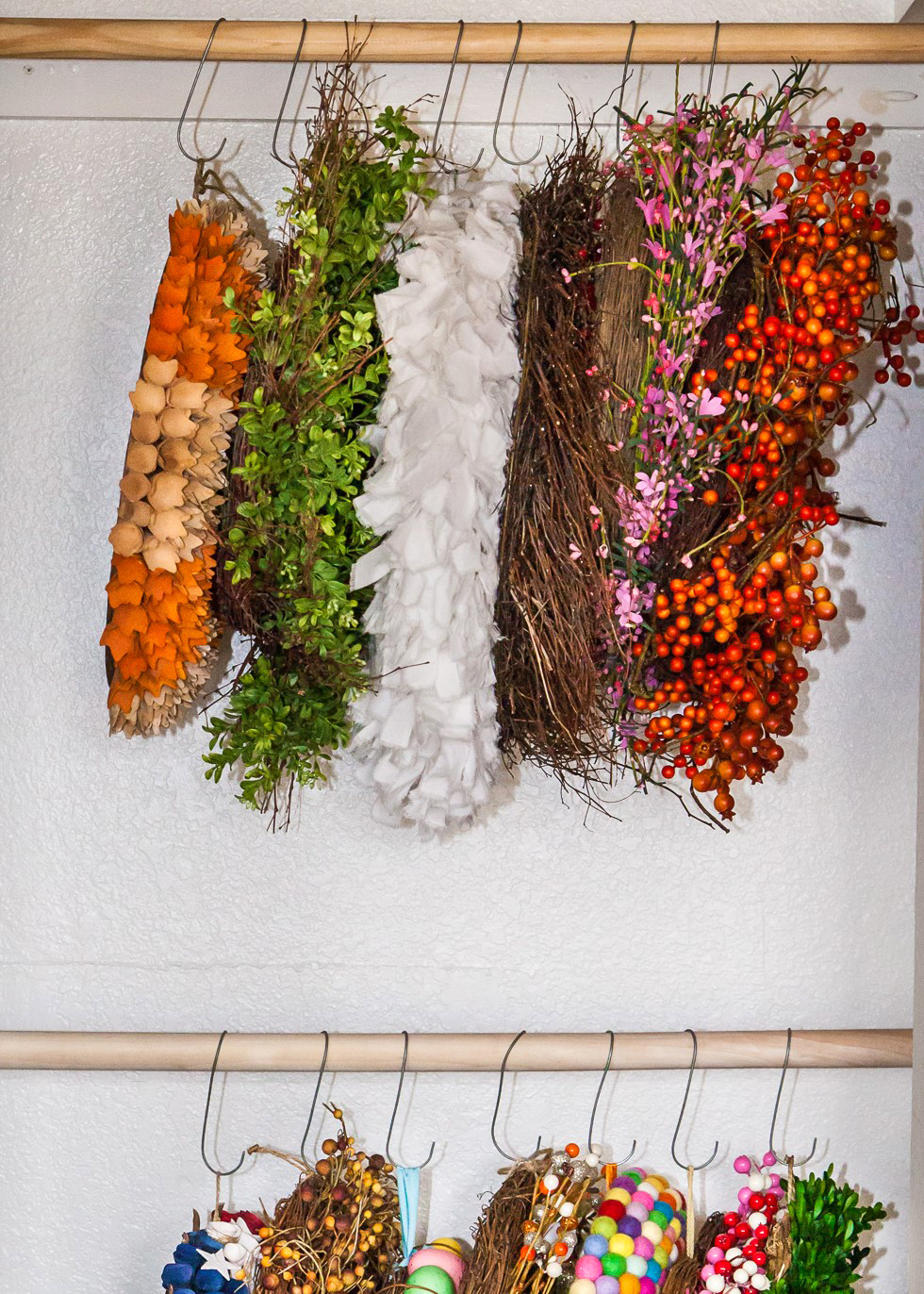 Assorted holiday wreaths hanging on closet rod