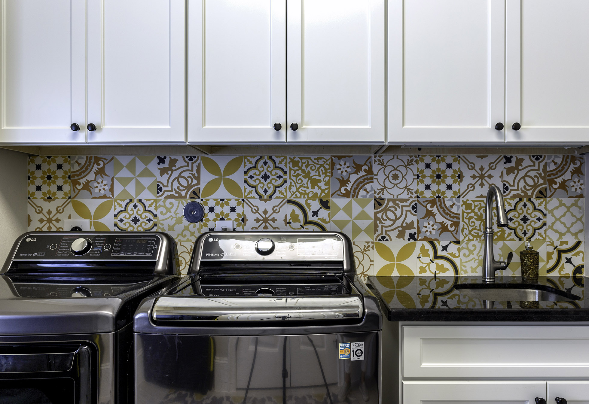 Washer and dryer side beside in front of colorful tile