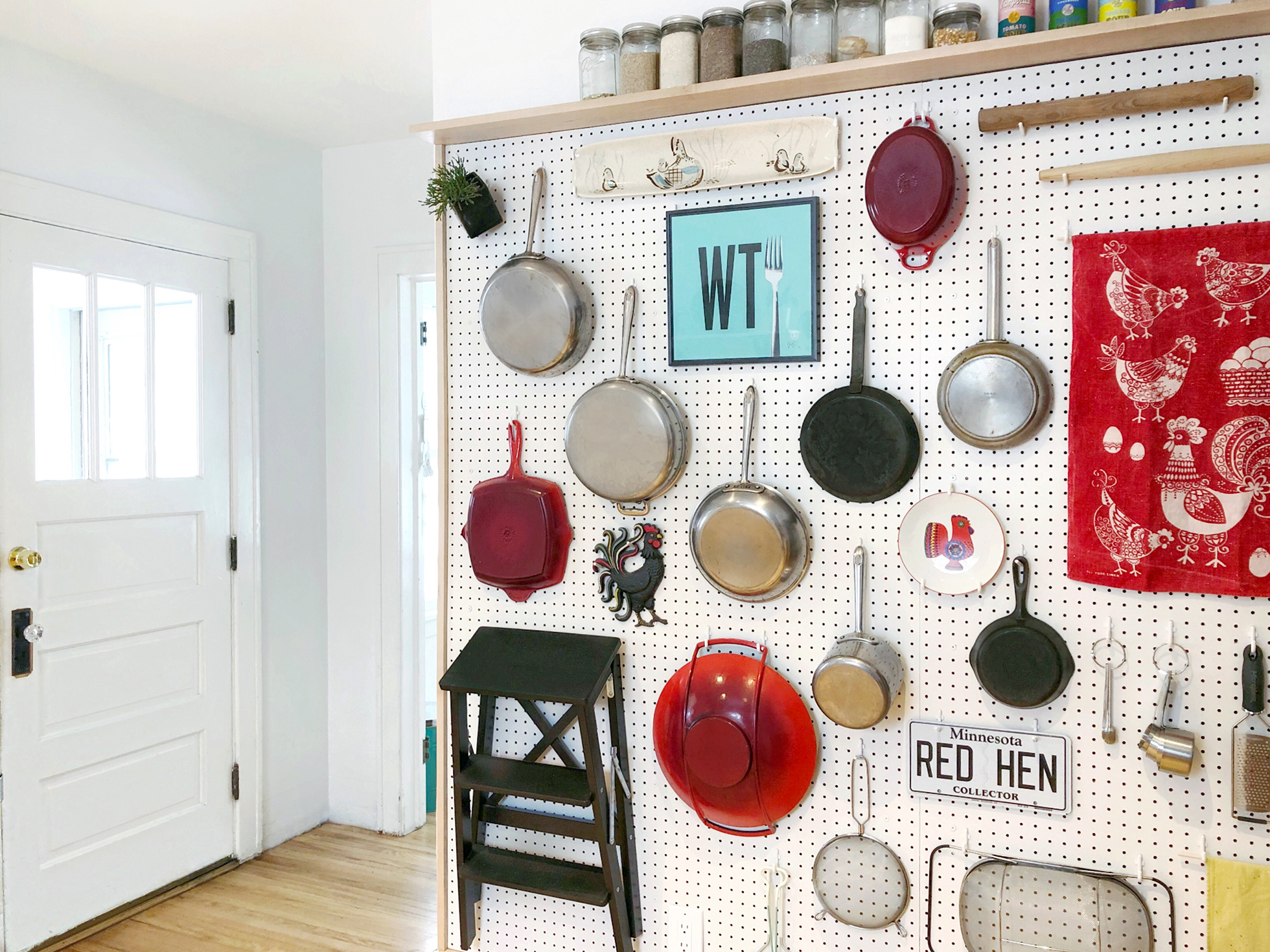 Pegboard in kitchen hanging pots, pans, and other items
