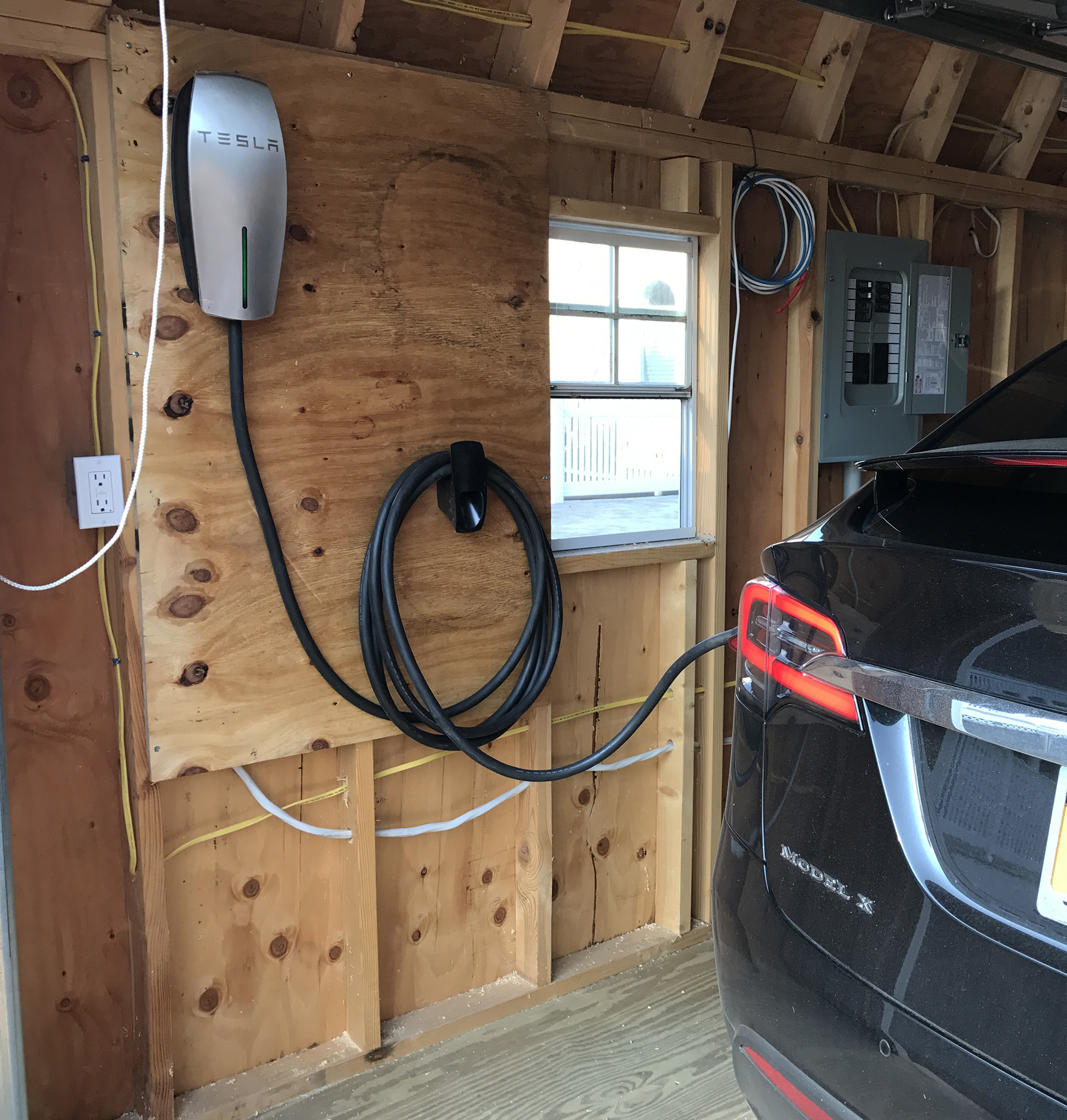 Wood-paneled garage with black electric car charging