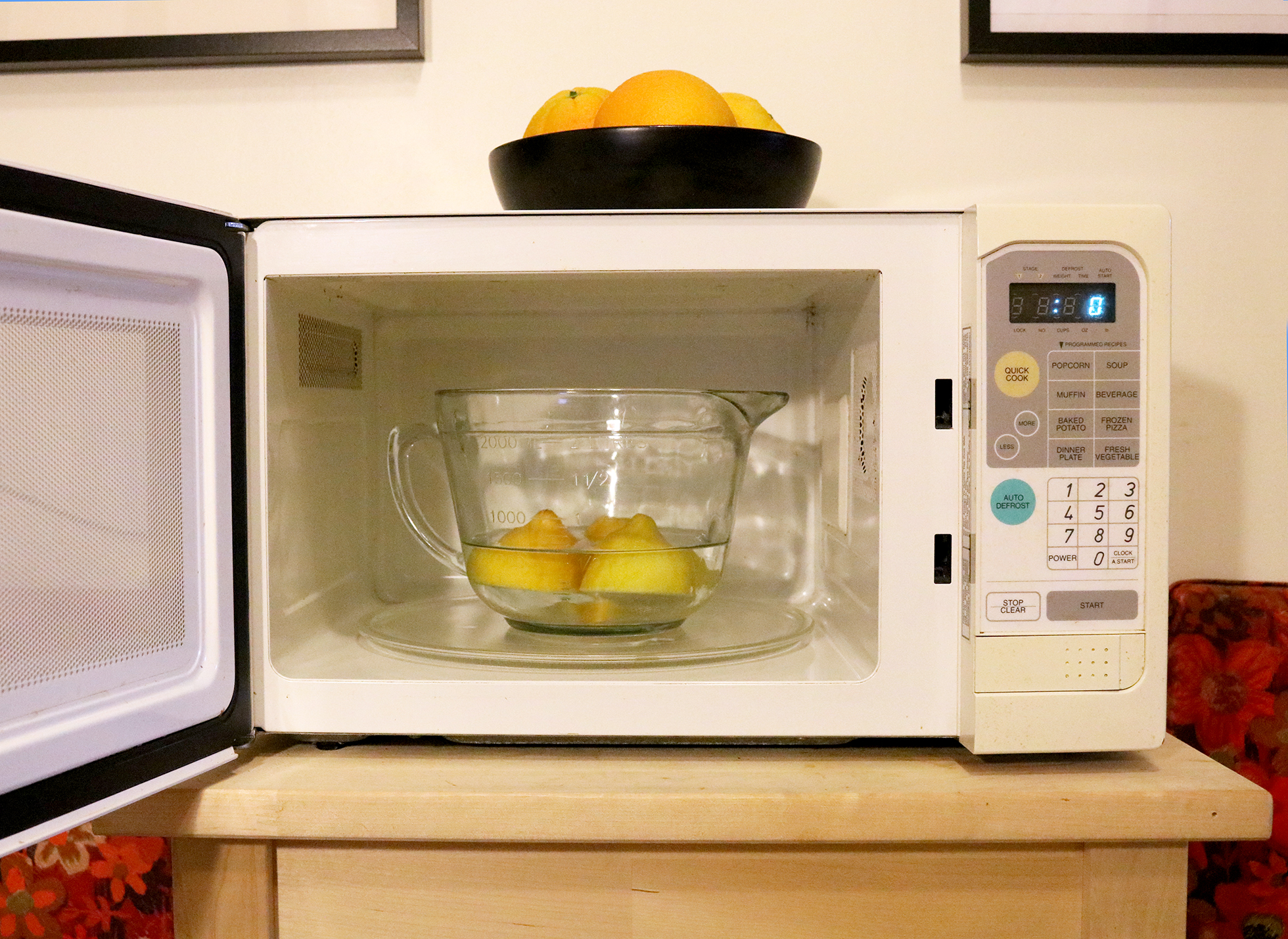 Three lemons in a bowl of water inside a microwave
