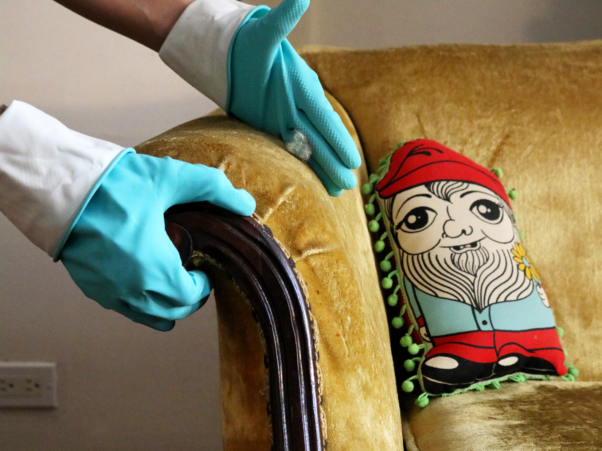 Rubber gloved hands wiping pet hair from a couch