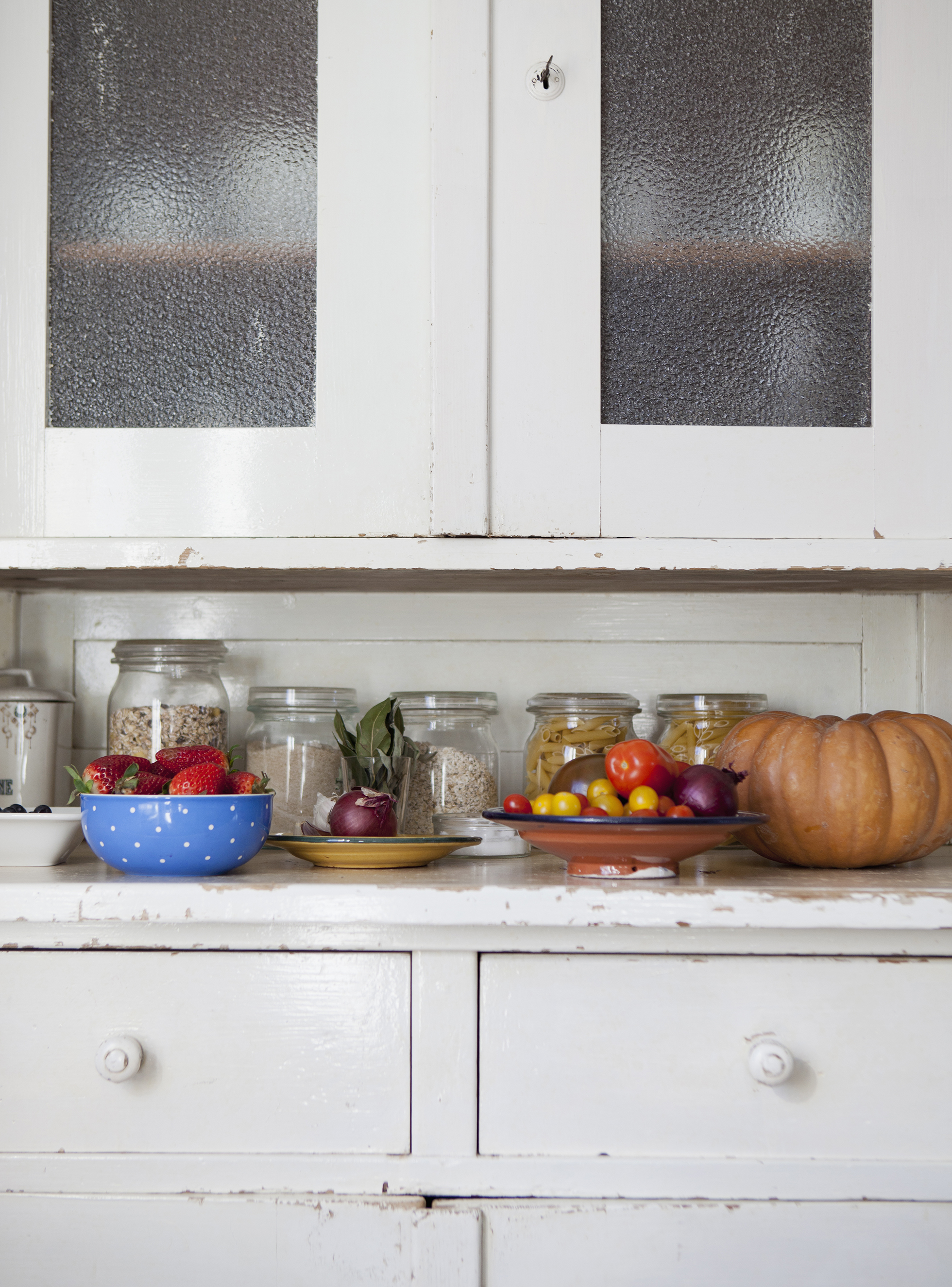 White kitchen cabinets with counters cluttered with objects
