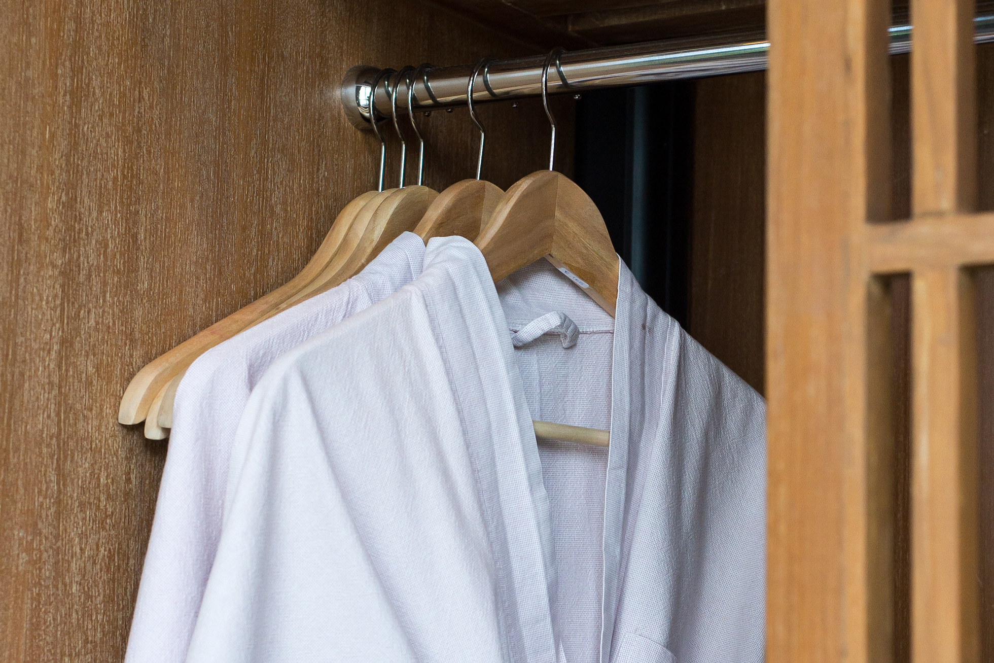 White cotton robes on hangers in a wood closet