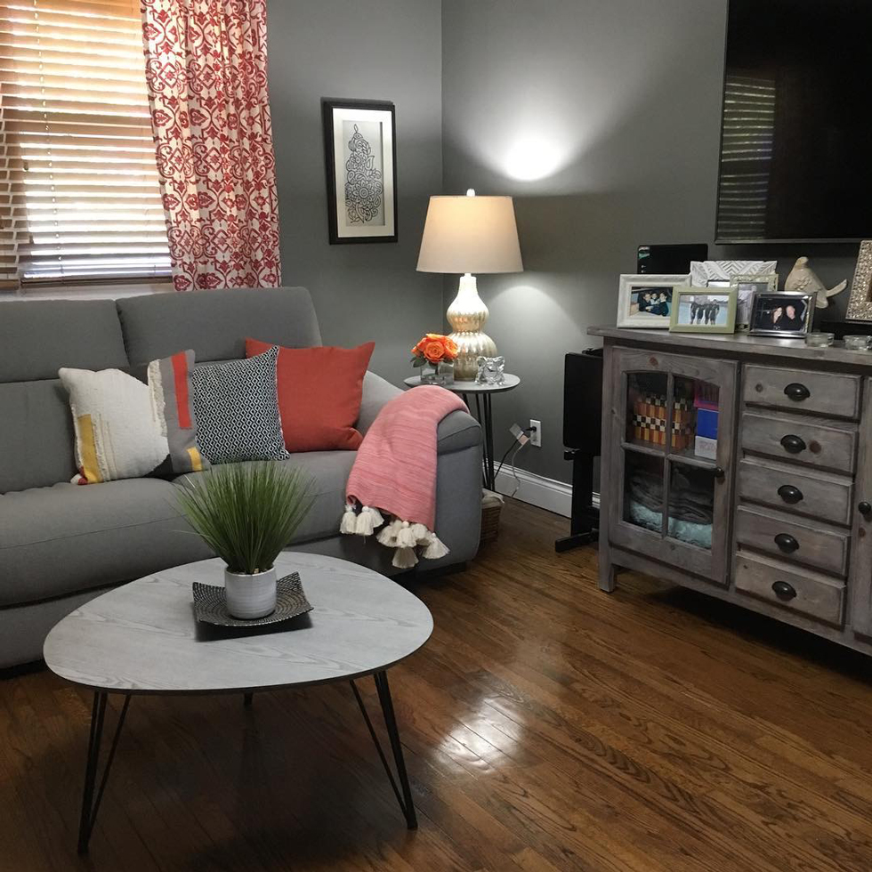 A living room with blue-gray walls, wood floors, and a lamp
