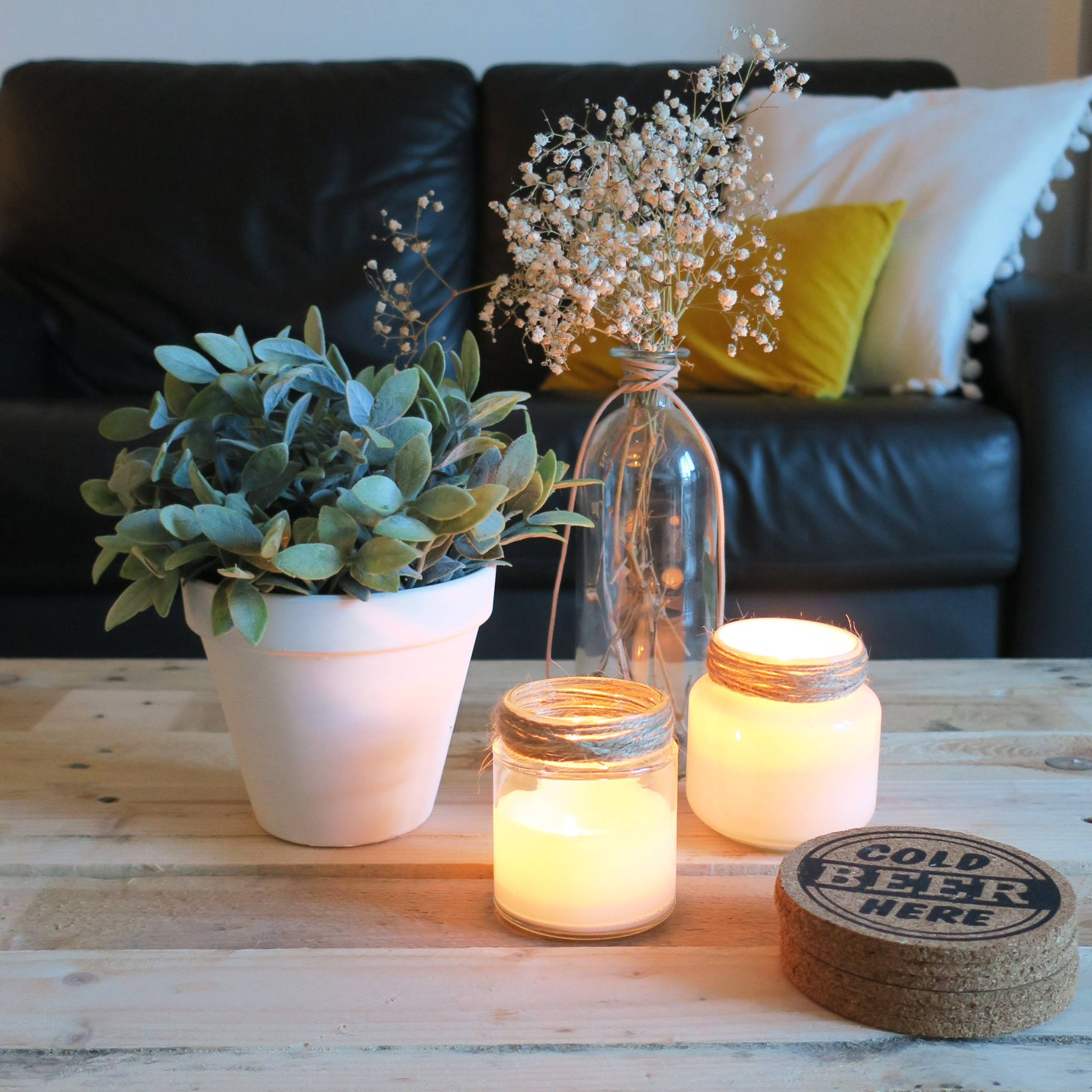 Two light candles on a wood table in a living room