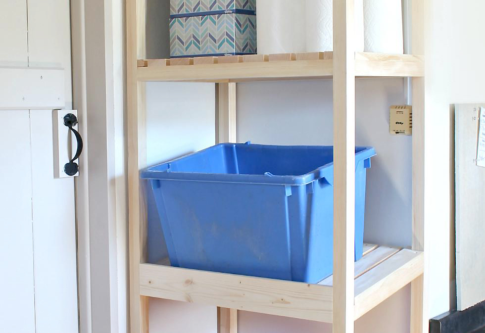 Wood tower in a garage with blue and red recycling bins