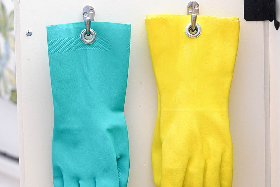 A blue and yellow pair of gloves with grommets under sink