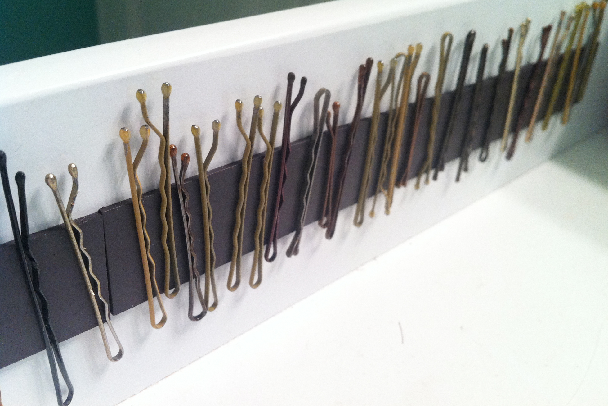 A white bathroom drawer with magnetic strip and bobby pins