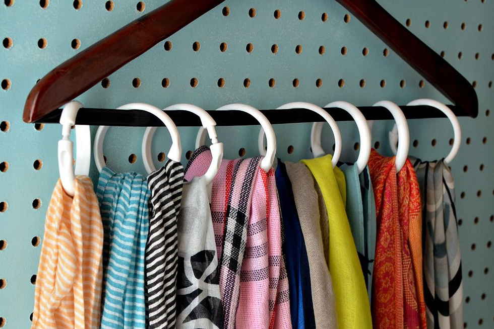 Colorful scarves on a wood hanger on a blue pegboard
