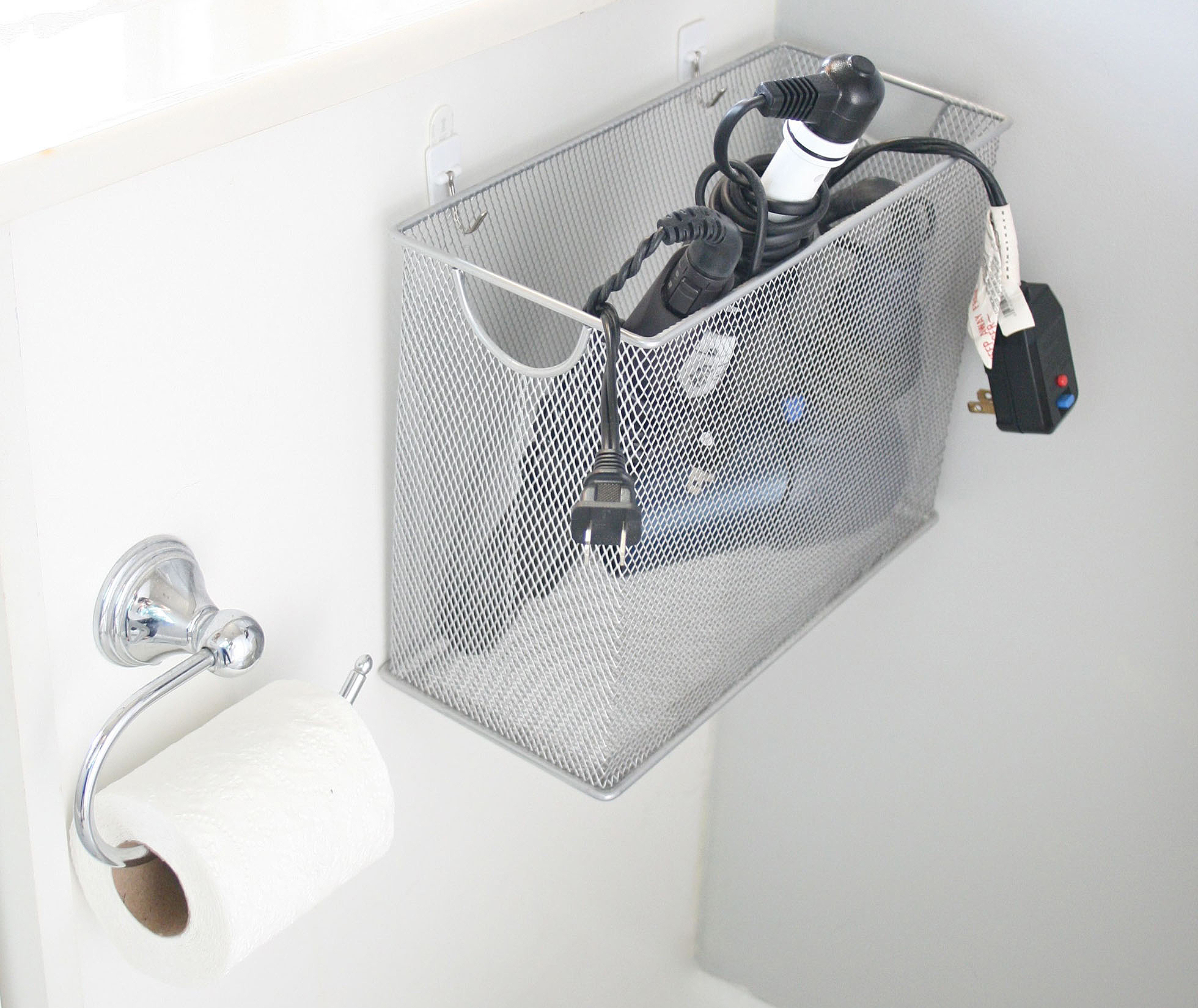A wire basket attached to a white cabinet in a bathroom