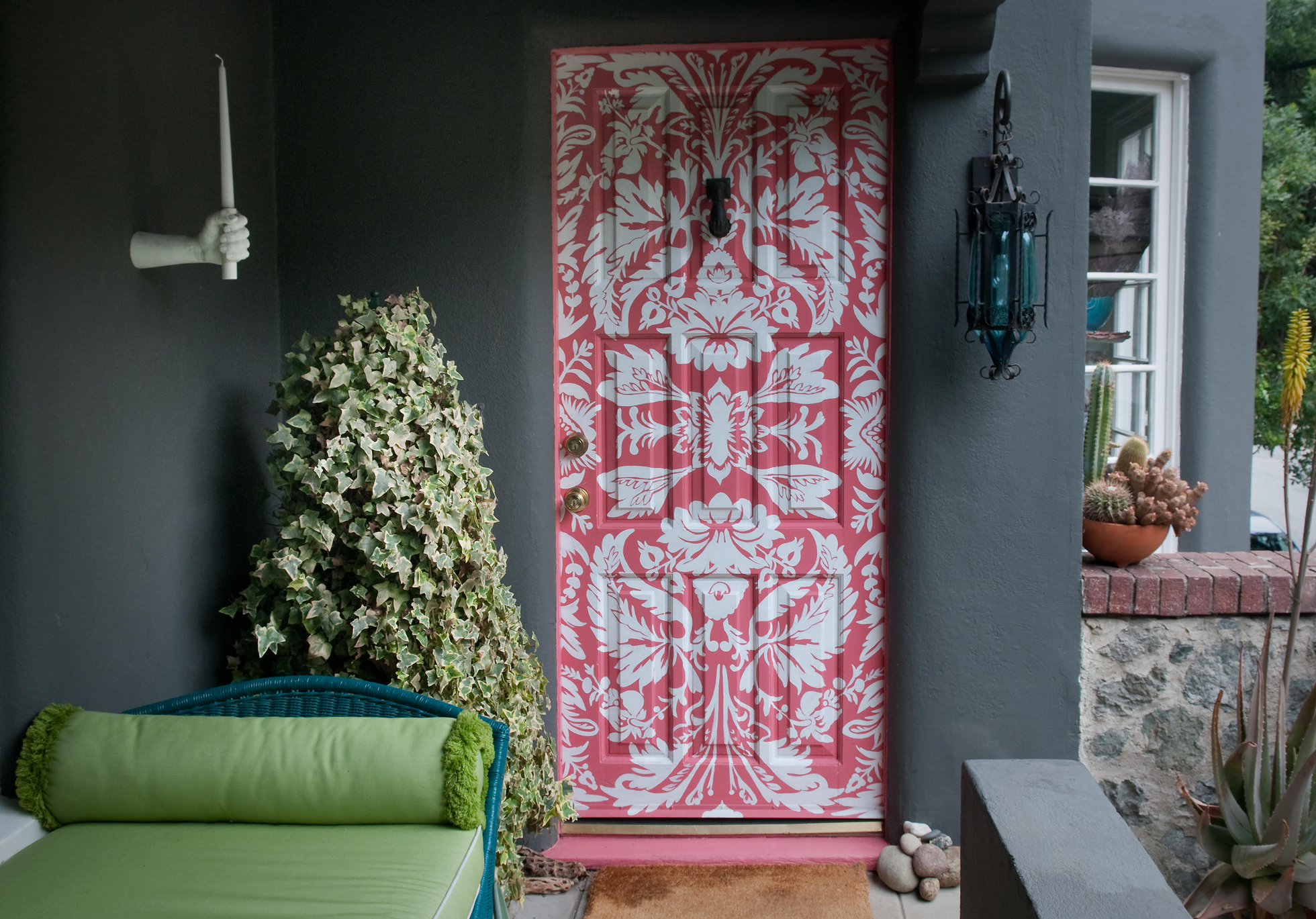 A gray stucco home with a pink and white stencil front door