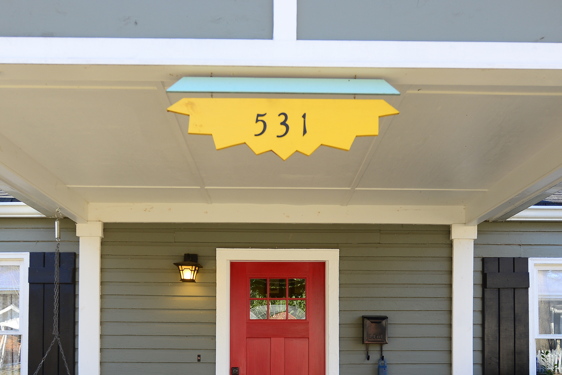 Black house numbers on a piece of yellow painted wood