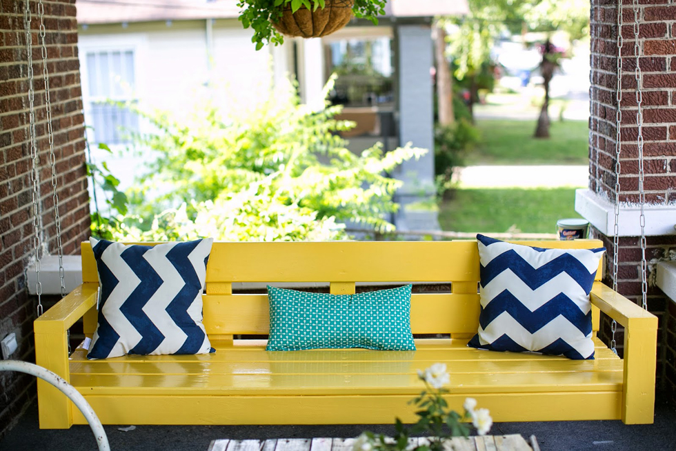 Bright yellow porch swing on a brick front porch