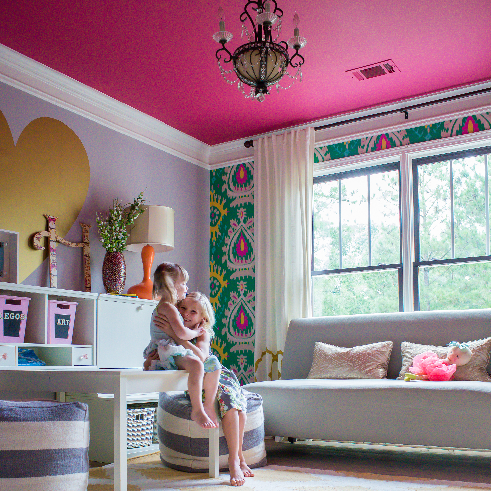 Two girls sitting in a colorful home office w/ pink ceiling