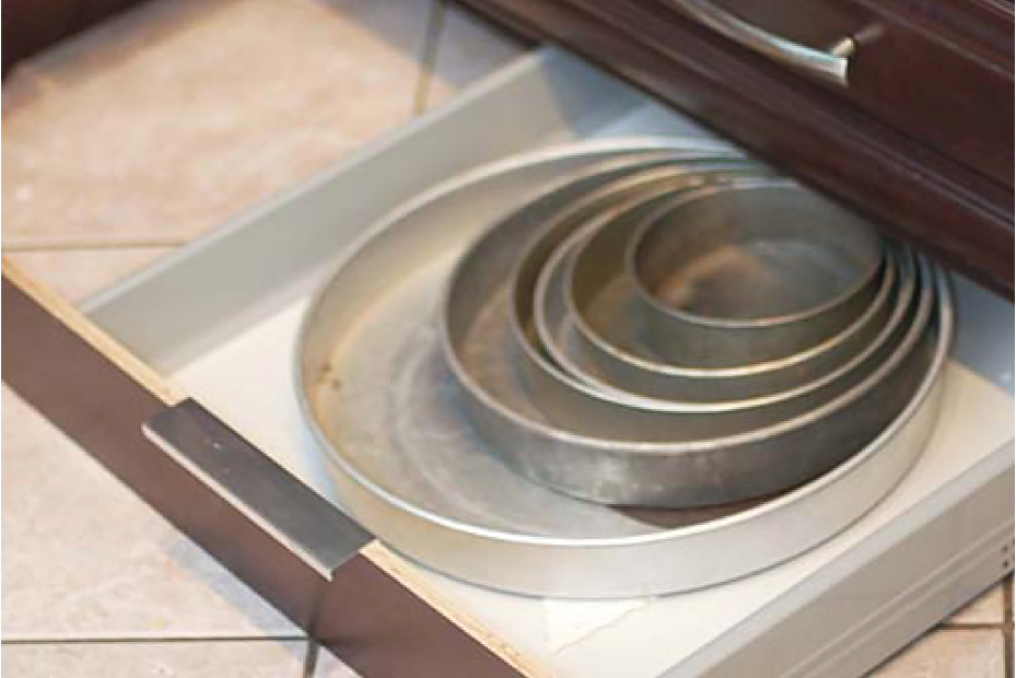 Wood toekick kitchen drawer filled with baking dishes