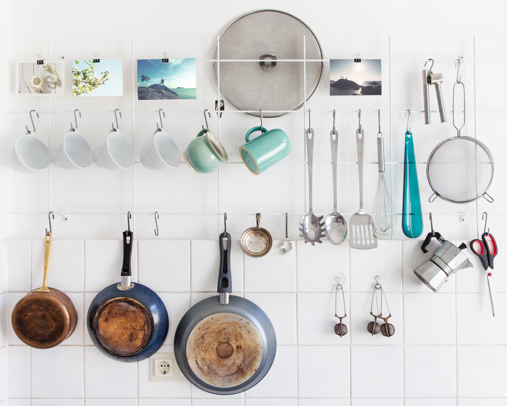 A white kitchen with hanging pots, pans, and utensils