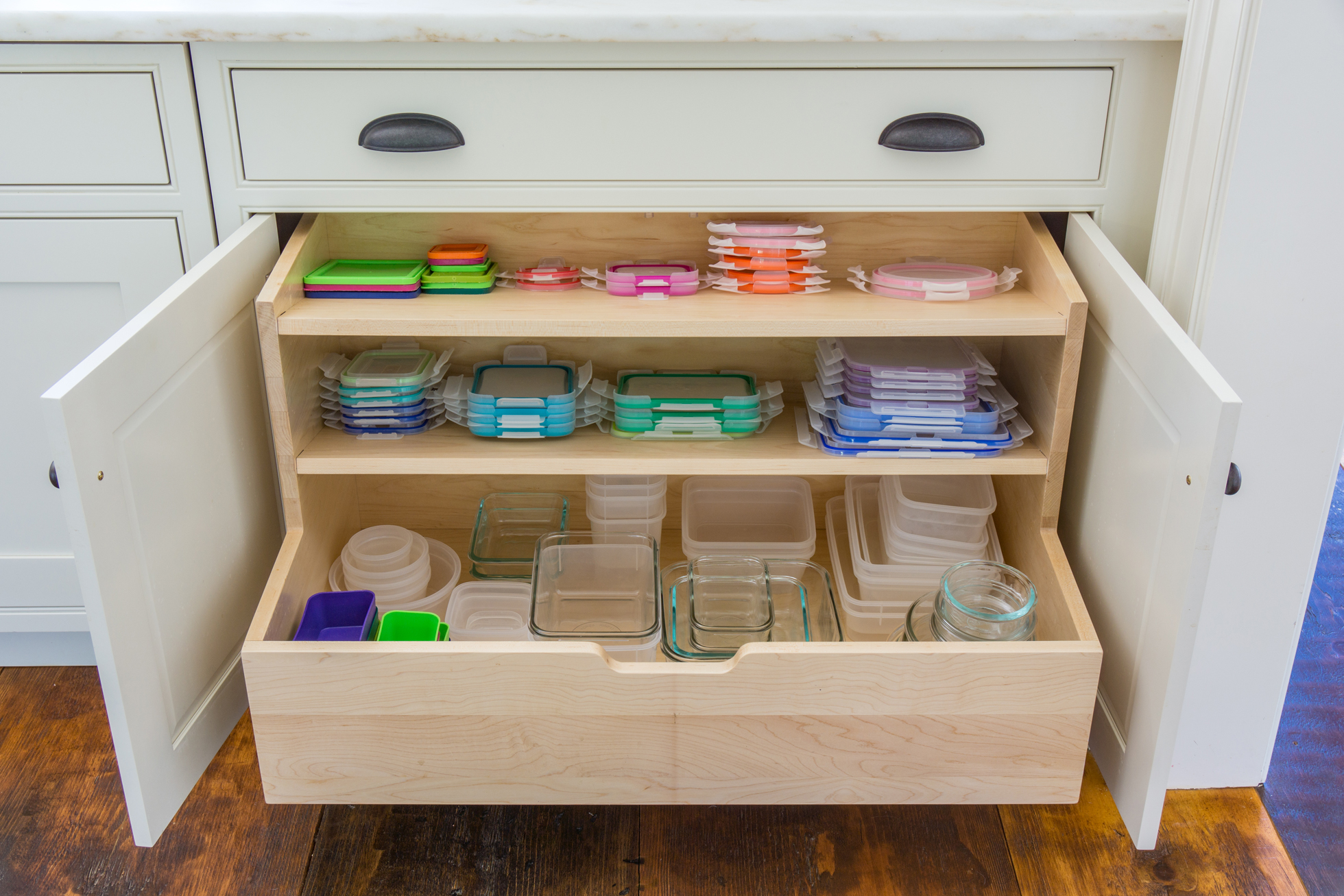 Tupperware and lids in a wood drawer in a kitchen