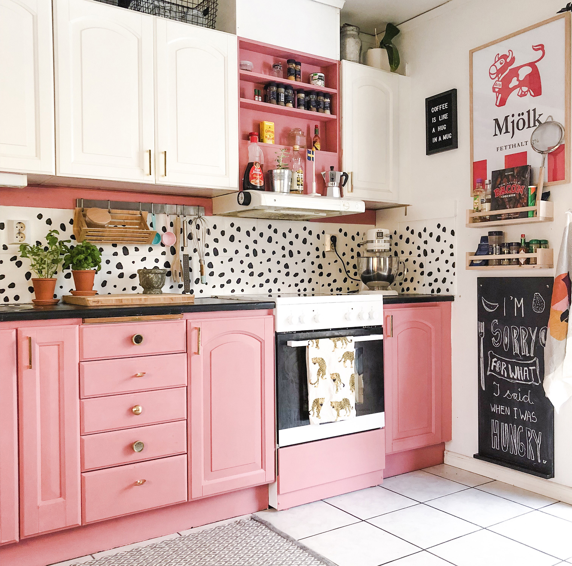 Pink, black, and white kitchen with pink and white cabinets