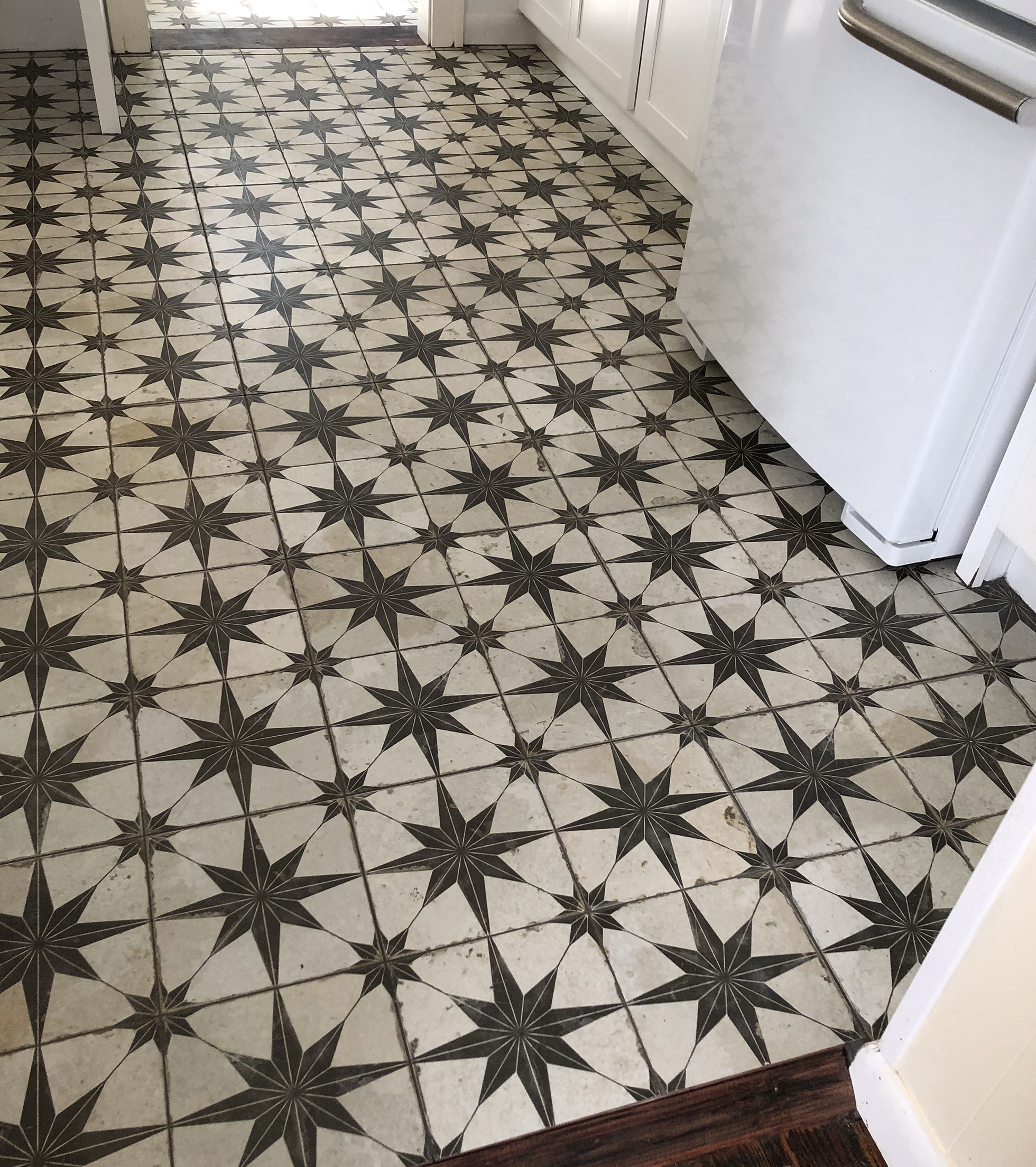 Kitchen floor remodeled with black and white sunburst tiles