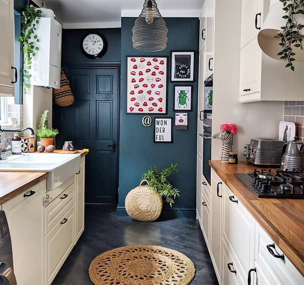 White kitchen with dark blue accent wall covered in photos
