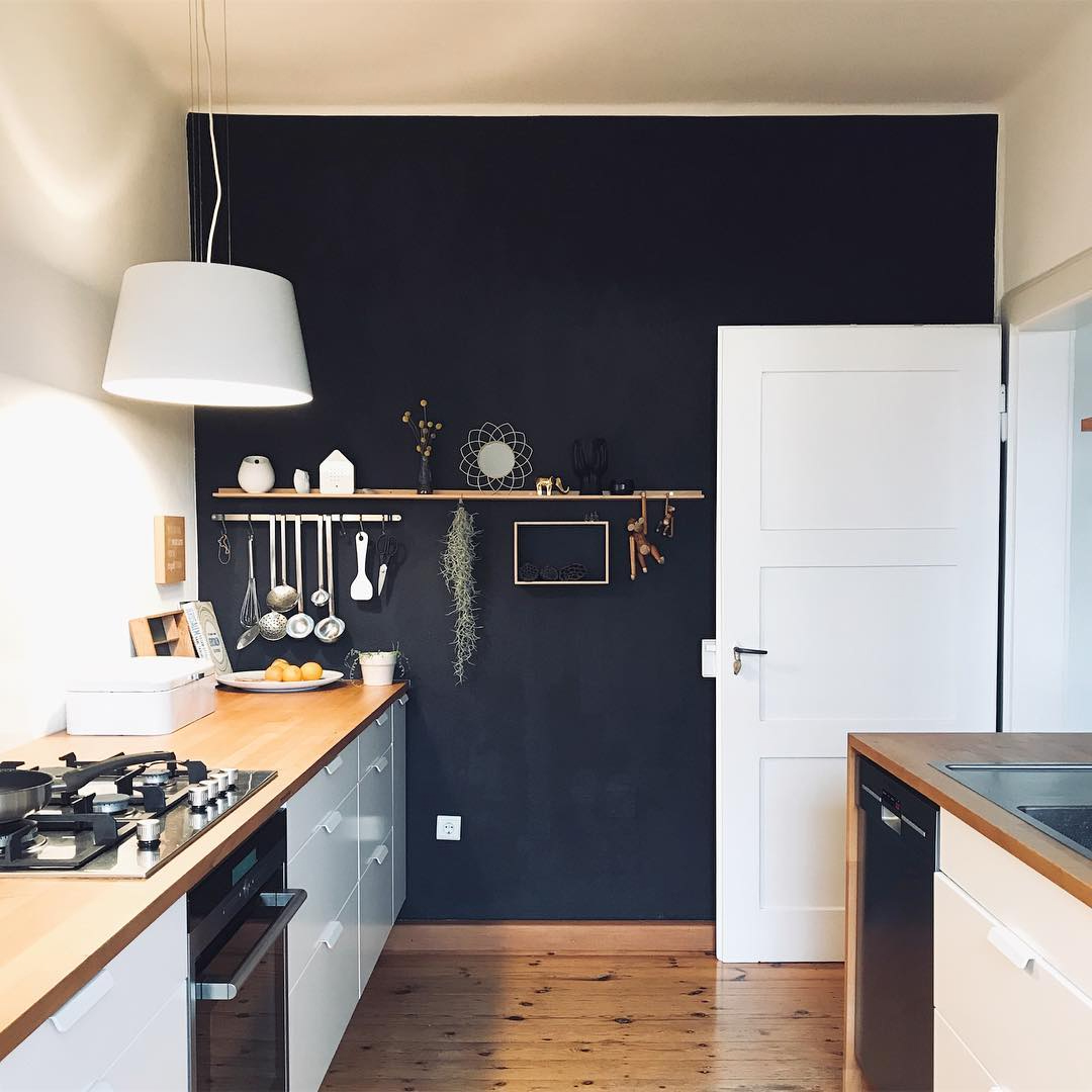 White kitchen with dark blue accent wall and floating shelf