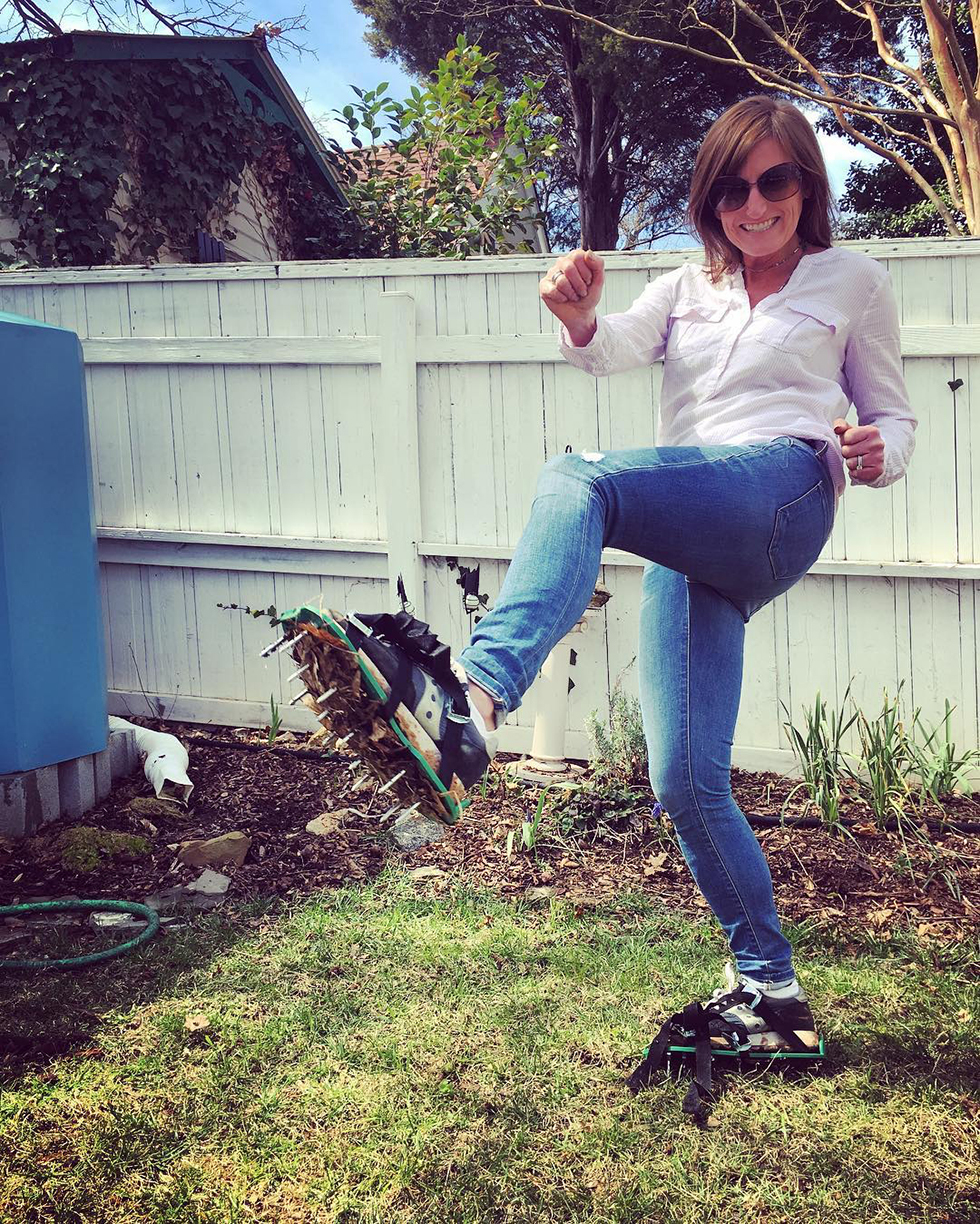 Woman in white shirt and jeans using lawn aerator shoes