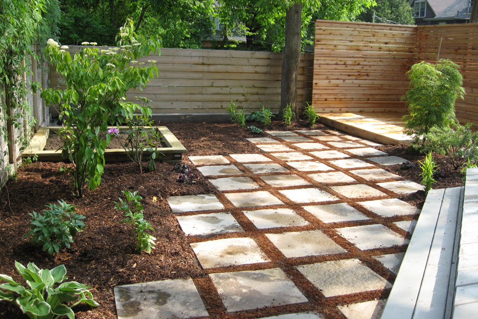 Pine bark in a backyard with square concrete pavers