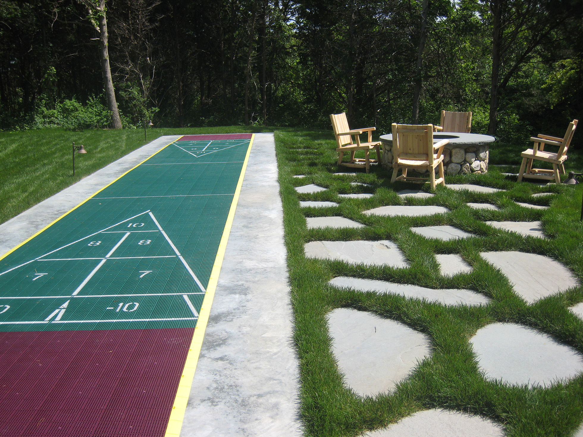Back yard shuffle board beside fire pit with chairs