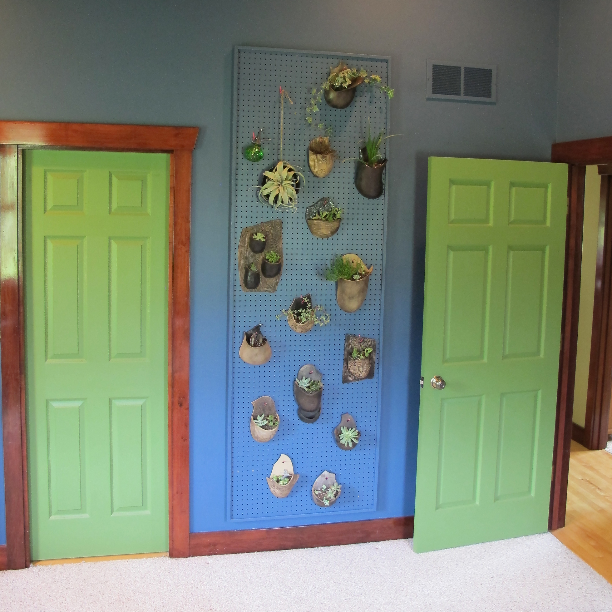 An blue pegboard in a blue room with green plants