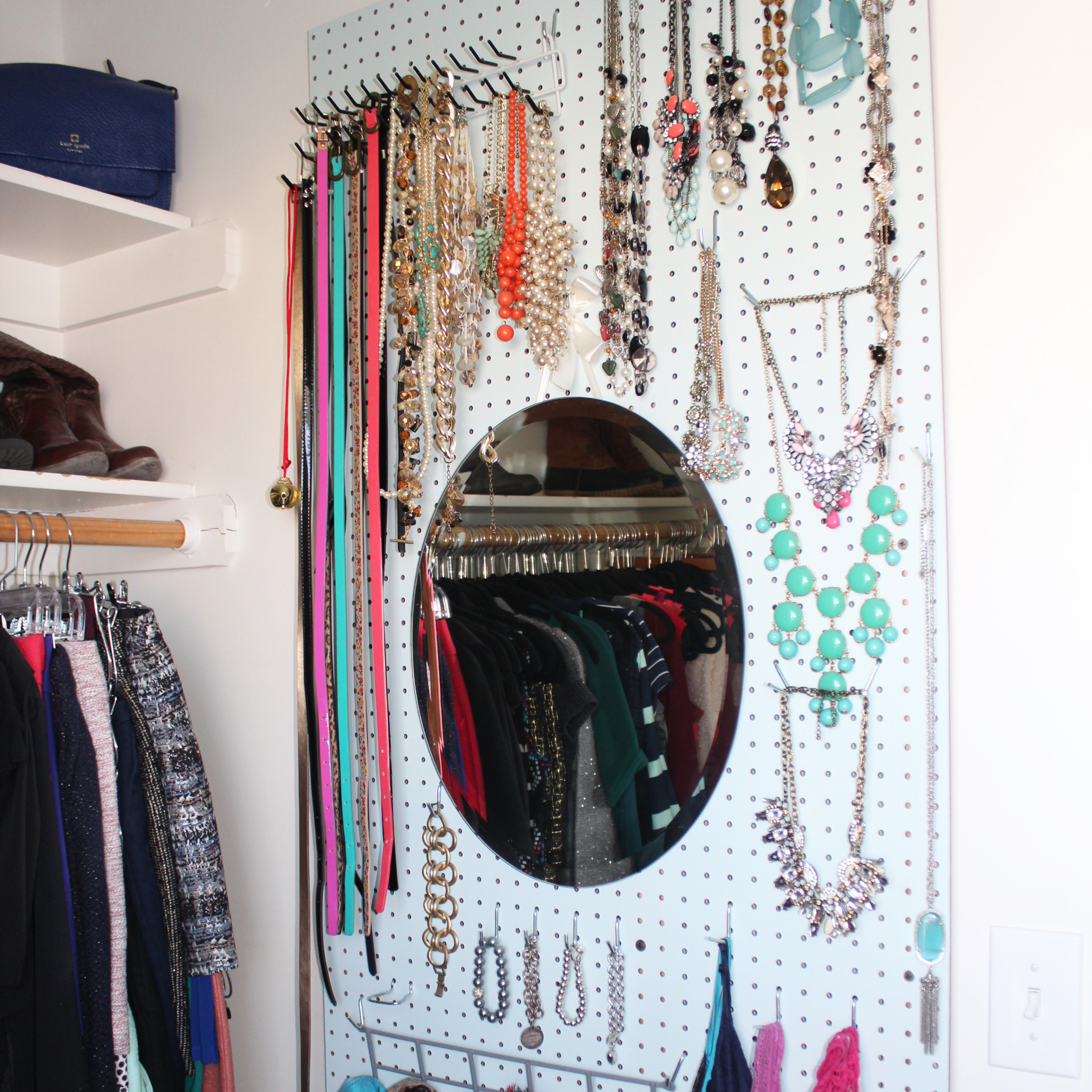 White pegboard with necklaces and scarves in a closet