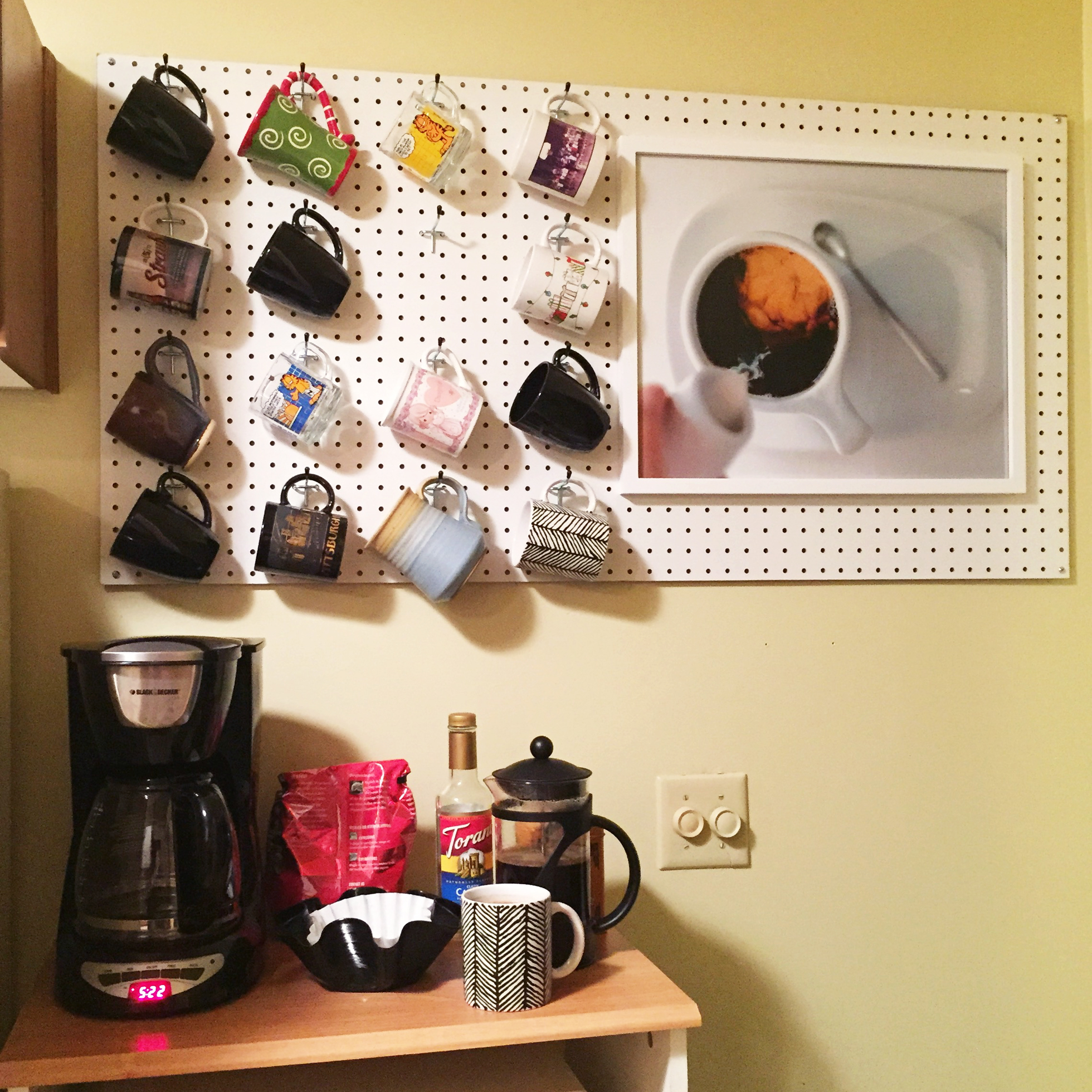 A white pegboard in a kitchen with coffee mugs