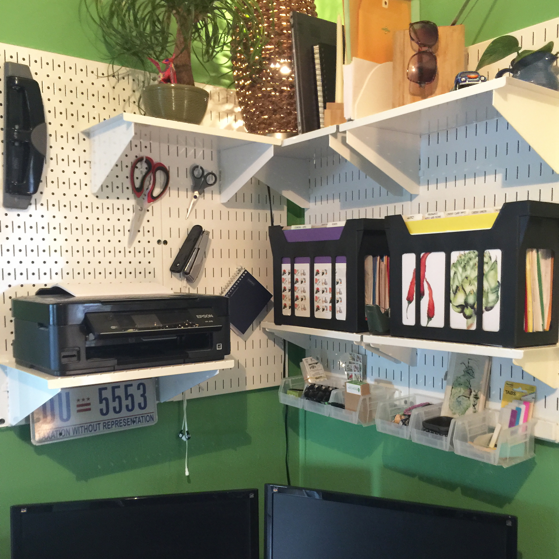 A white pegboard against a green wall in a home office